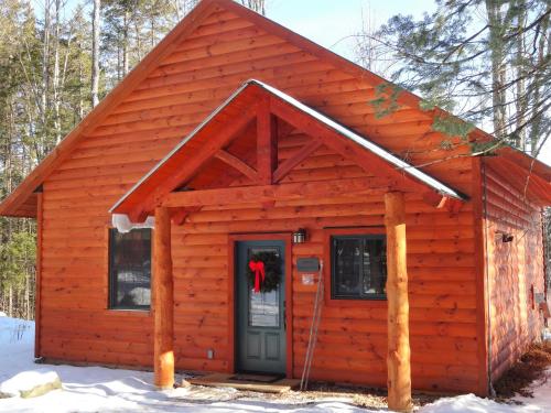 a log cabin with a door in the snow at Robert Frost Mountain Cabins in Middlebury