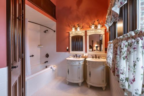 a bathroom with two sinks and a tub and a mirror at Steele Mansion Inn & Gathering Hub in Painesville