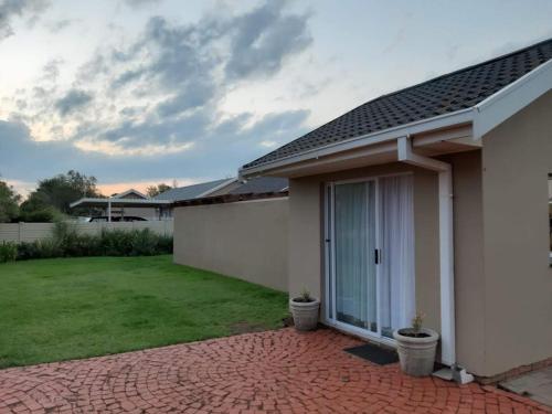 ein weißes Haus mit einer Backsteinterrasse und einem Hof in der Unterkunft Gathering Guesthouse - Aloe room in Bloemfontein