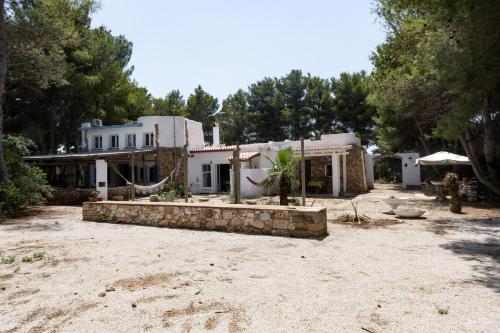 une grande maison blanche avec des arbres devant elle dans l'établissement Casa Vacanze Capurre "Trulli e Pajare a due passi dal Pizzo", à Gallipoli