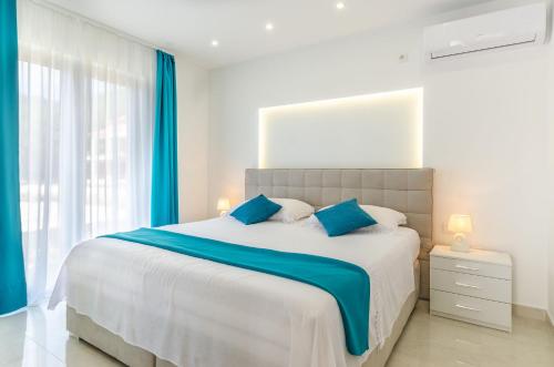 a bedroom with a large bed with blue pillows at KORČULA Antea Apartment in Prizba
