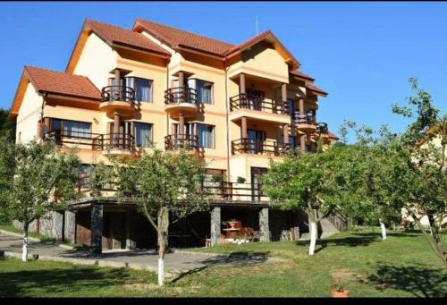 a large apartment building with balconies and trees at Pensiunea '' LA PAPA'' in Huta Certeze