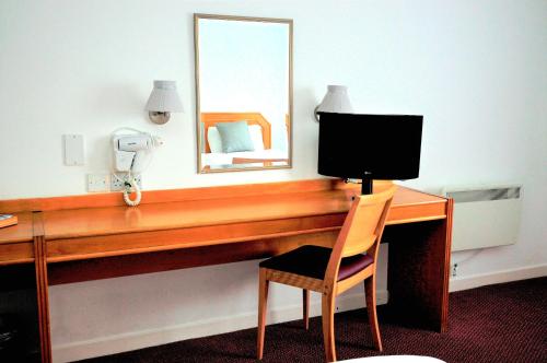 a desk with a computer monitor and a chair at Days Inn Hamilton in Hamilton