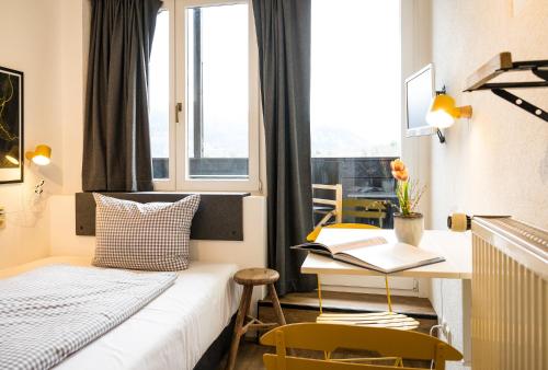 a bedroom with a bed and a desk and a window at Das Nordberg Guesthouse in Garmisch-Partenkirchen