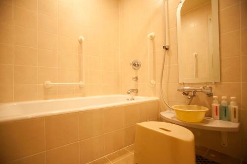a bathroom with a tub and a toilet and a sink at Hotel Grand Arc Hanzomon in Tokyo