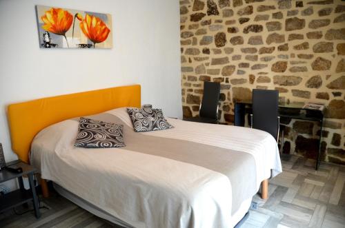 a bedroom with a bed and a stone wall at Gîtes et Chambres - Les Buissonnets in La Turballe