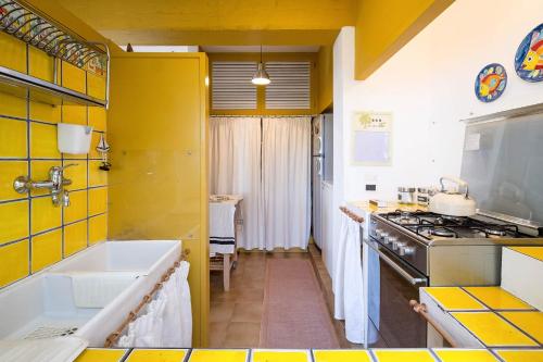 a yellow and white kitchen with a tub and a stove at VILLA LAURA MARIE in Porticello