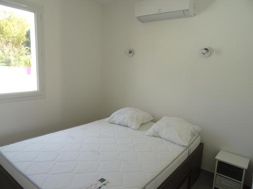 - un lit blanc avec deux oreillers dans une chambre dotée d'une fenêtre dans l'établissement Résidence Château Saint Martin, à Saint-Martin-dʼArdèche