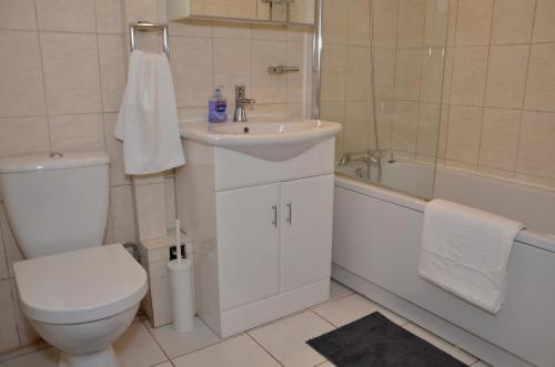 a bathroom with a sink and a toilet and a bath tub at Croydon apartment with parking in London