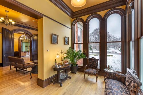a living room with a table and chairs and windows at Steele Mansion Inn & Gathering Hub in Painesville