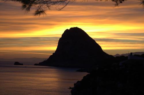 a mountain on the water with a sunset in the background at VILLA LAURA MARIE in Porticello