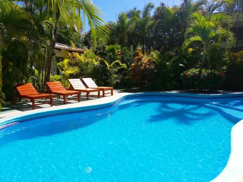 a swimming pool with two chairs and a pool at Villas Verdes in Sámara