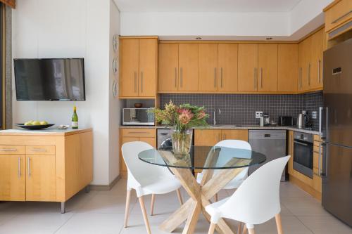 a kitchen with a glass table and white chairs at #508 Cartwright - Great Value in Cape Town