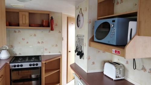a small kitchen with a stove and a microwave at 6 Berth Golden Sands Ingoldmells Sahara in Ingoldmells