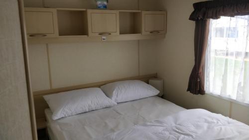 a small bedroom with a bed and a window at 6 Berth Golden Sands Ingoldmells Sahara in Ingoldmells