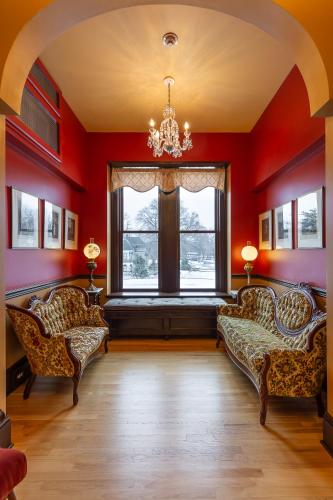 a living room with two chairs and a window at Steele Mansion Inn & Gathering Hub in Painesville