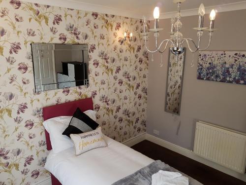 a bedroom with a bed with a mirror and flowers at Slough Centre Townhouse with driveway parking for up to two cars in Slough