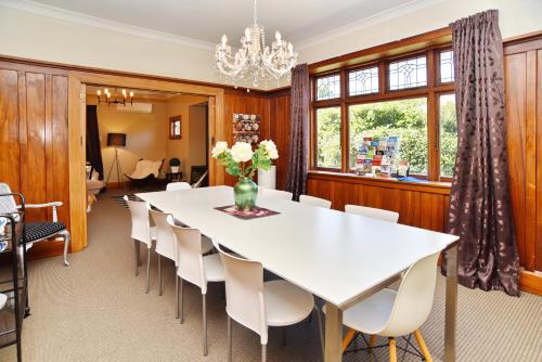 a dining room with a white table and chairs at Racecourse Villa - Classic 1935 Charm & Space in Christchurch