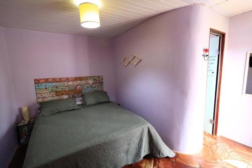 a bedroom with a bed in a purple wall at Pousada Trilha Violeta in Sao Jorge