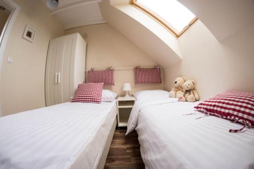 2 Betten in einem Zimmer mit einem Teddybären dazwischen in der Unterkunft Piaskowa Polana in Dębki