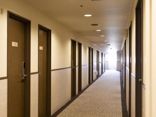 an empty hallway of a building with doors and a hallwayngth at Nishitetsu Inn Kurosaki in Kitakyushu