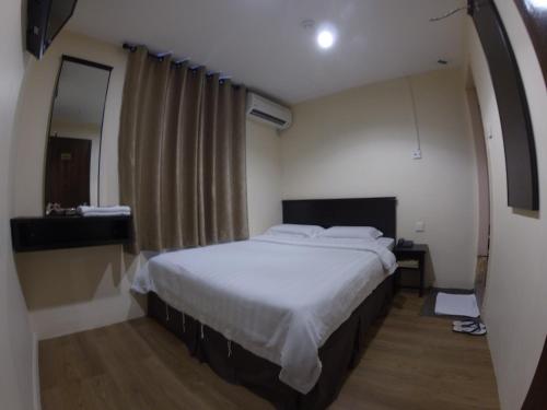 Hotel Kinabalu في كوتا كينابالو: غرفة نوم بسرير كبير في غرفة