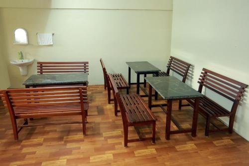 a group of wooden benches and tables in a room at Cherai Beach Palace in Cherai Beach