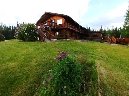 a log cabin with a grassy field in front of it at Northern Sky Lodge in Fairbanks