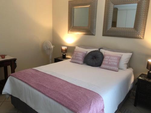a bedroom with a large bed with two mirrors on the wall at Innikol 26 in Mossel Bay