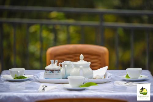 a table with tea pots and cups on it at Pine Trees Homestay in Adams Peak