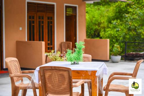 a table with a white table cloth and chairs at Pine Trees Homestay in Adams Peak