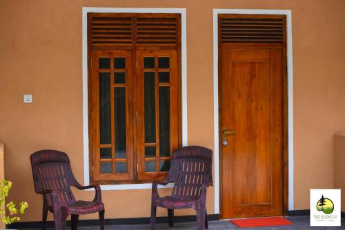 two chairs sitting in front of a house with a door at Pine Trees Homestay in Adams Peak