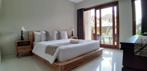 a bedroom with a large white bed and a window at Kyumari in Ubud
