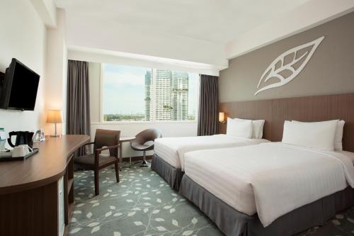 a hotel room with two beds and a desk at Swiss-Belinn Kemayoran in Jakarta