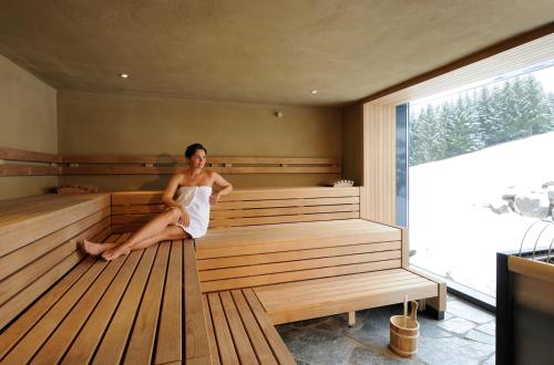 a woman is sitting in a sauna at Hotel Lindenwirt in Drachselsried