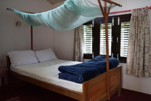 a bedroom with a canopy bed with a blue blanket on it at Forest Hideaway Resort Pvt Ltd in Bhurkīā