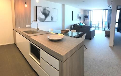 a kitchen with a counter top and a living room at Qube Broadbeach Ocean View Apartments in Gold Coast