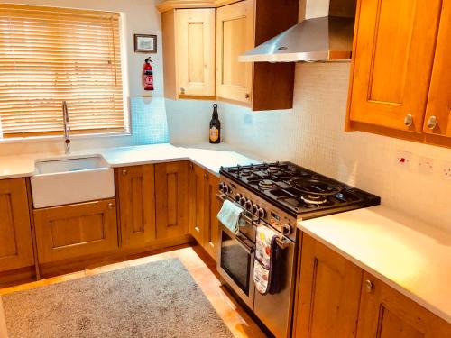 une cuisine avec des armoires en bois et un four à plaques de cuisson dans l'établissement Tarporley Holiday Cottage, à Tarporley