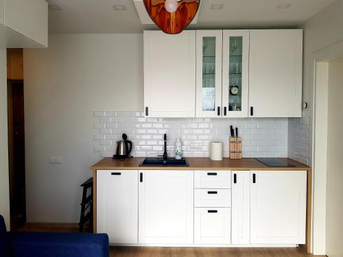a kitchen with white cabinets and a wooden counter top at Malūno Vilos apartamentai in Palanga