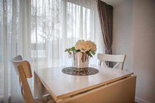 a vase of flowers on a table in front of a window at Dubingių apartamentai Nr. 2 in Vilnius