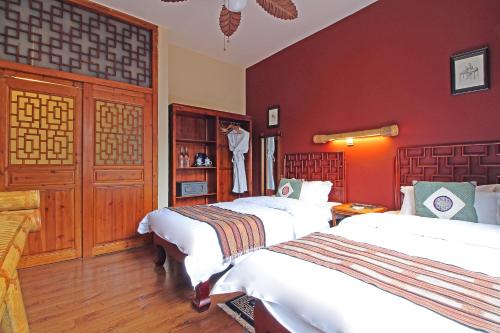 two beds in a room with red walls at Yangshuo Village Inn Boutique Hotel in Yangshuo