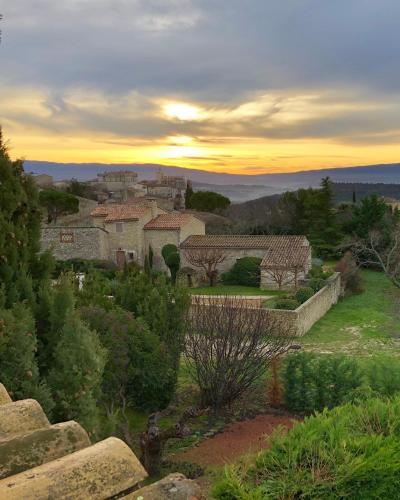 a view of a village with a sunset in the background at Domaine de l'Enclos in Gordes