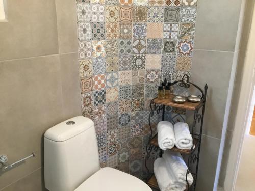 a bathroom with a toilet and a tiled wall at Athens-Plaka, Peter’s beautiful apartment in Temple of Zeus in Athens