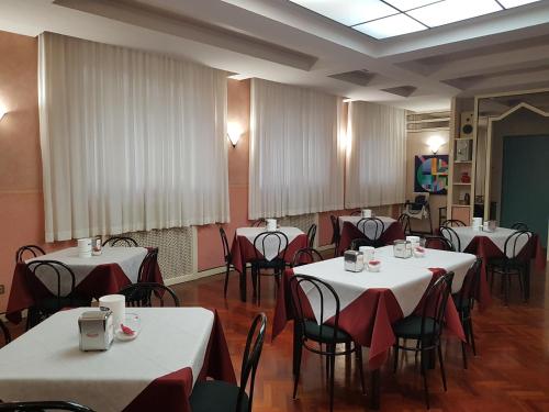 Hotel Nettuno في بورتو سان جورجيو: غرفة طعام مع طاولات وكراسي مع مفارش مائدة بيضاء وحمراء