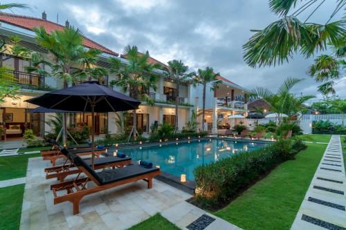 an image of a resort pool with benches and an umbrella at Puri Uma Ratu by RPM in Seminyak