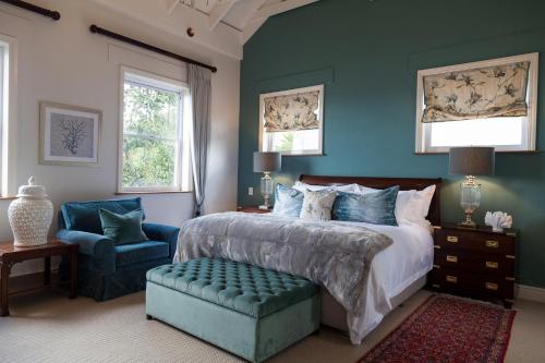 a bedroom with a bed and a blue wall at Tintswalo Boulders in Simonʼs Town