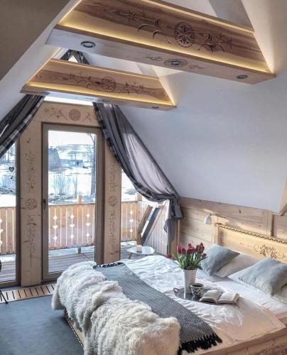 a bedroom with a large bed and a large window at Stylowa Chata in Zakopane