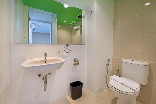 W łazience znajduje się umywalka, toaleta i lustro. w obiekcie Whiz Prime Hotel Megamas Manado w mieście Manado