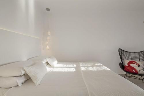 a white bedroom with a bed and a chair at Art Hotel Santorini in Pirgos