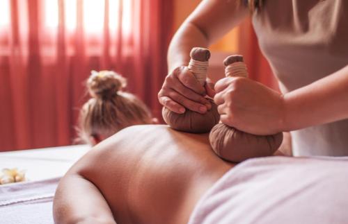 a woman sitting on a bed holding two hair brushes at Almanity Hoi An Resort & Spa in Hoi An